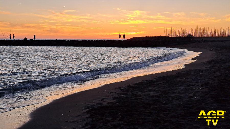 Ostia Lido, lo spettacolo del tramonto nella zona di Ponente. Sullo sfondo le scogliere del porto e le caratteristiche strutture in legno sulla spiaggia, incorniciate dai colori accesi del cielo di fi Ostia Lido, lo spettacolo del tramonto nella zona di Ponente. Sullo sfondo le scogliere del porto e le caratteristiche strutture in legno sulla spiaggia, incorniciate dai colori accesi del cielo di fi